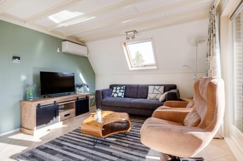 a living room with a couch and a tv at Gaai I Prachtige Vakantiewoning nabij Bos in Zwiggelte