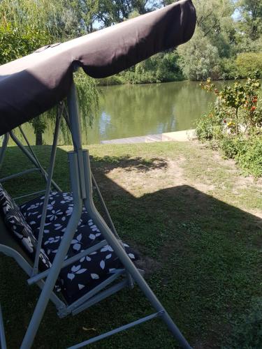 a chair under an umbrella next to a body of water at Klára apartman in Sárospatak