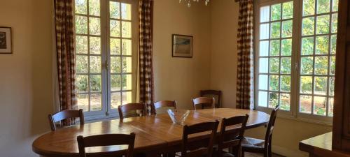 d'une salle à manger avec une table en bois et quelques fenêtres. dans l'établissement Rivière Retreat, à Bergerac
