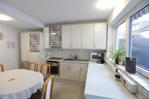 cocina con armarios blancos, mesa y fregadero en City Wohnung 12 B, en Brühl