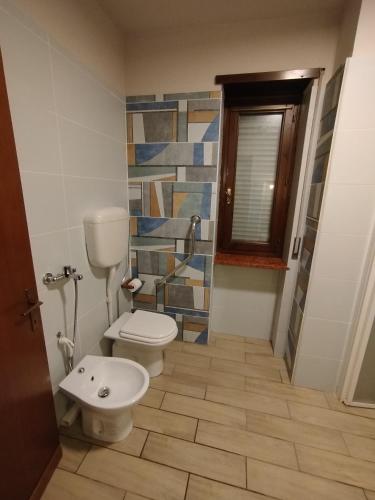 a bathroom with a toilet and a tile wall at Hotel Milano San Giovanni Lupatoto in San Giovanni Lupatoto