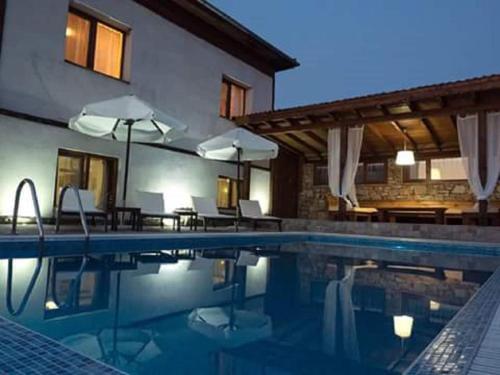 a pool with chairs and umbrellas next to a building at Villa Leventy in Banya
