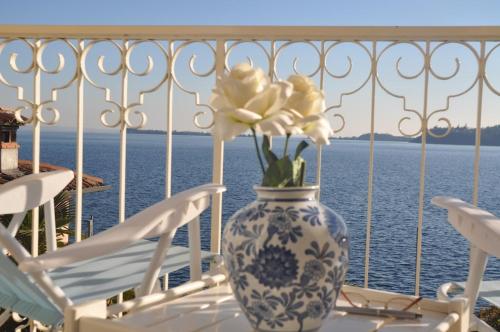a blue and white vase with flowers on a table on a balcony at Apartment La Rosa in Gardone Riviera