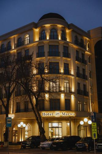 a hotel building with cars parked in front of it at Hotel Marwa Tashkent Pool&Spa in Tashkent