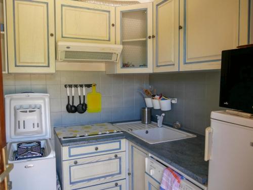 une cuisine avec des armoires blanches, un évier et un réfrigérateur dans l'établissement T2 Bormes les Mimosas - La Favière, à Bormes-les-Mimosas