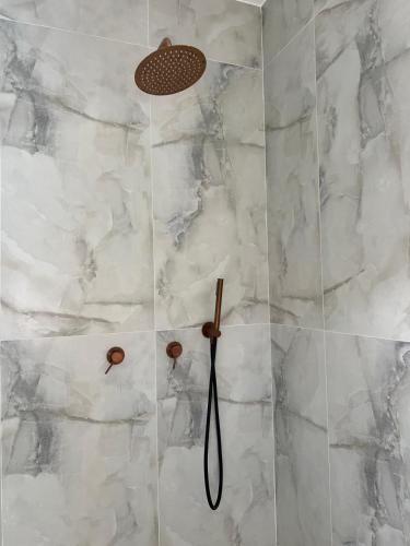 a shower with white marble walls and a shower head at vVצאנז - נופש מפנק in Netanya