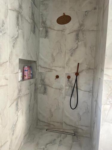 a bathroom with a shower with white marble walls at vVצאנז - נופש מפנק in Netanya