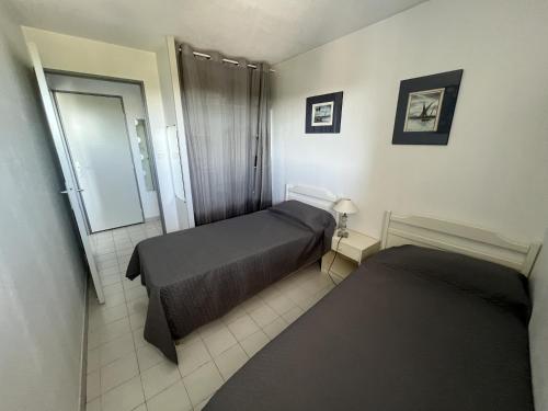 une petite chambre avec deux lits et un miroir dans l'établissement Sol-y-Days Bali, agréable appartement à vivre, à La Grande Motte