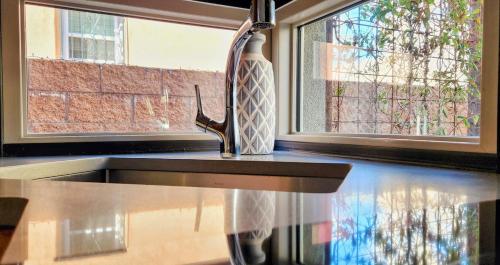 a sink in a kitchen next to two windows at Chic Townhome Haven rooted Downtown in Albuquerque