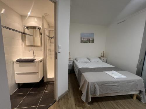 une chambre avec un lit, un lavabo et un miroir dans l'établissement Sol-y-Days jardins du couchant, à La Grande Motte