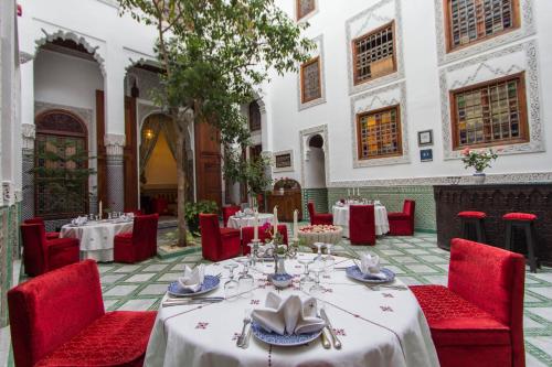 a dining room with tables and red chairs at Riad - Dar Al Andalous in Fès