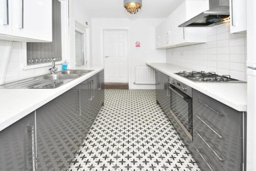 a white kitchen with a black and white tiled floor at Townhouse @ Lord Street Crewe in Crewe