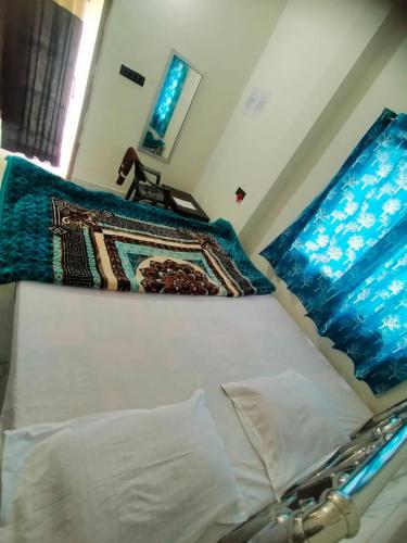 a white bed with a blue blanket on top of it at Shivay Guest house in Jasidih