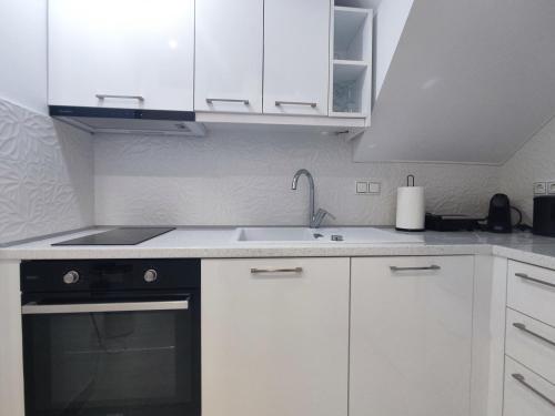 a white kitchen with a sink and a stove at Lusso di Campiello in Corfu Town