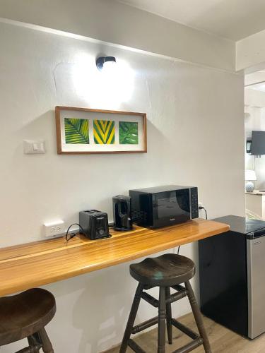 a desk with a computer and two stools at Bananaquit Tobago -Stay Near the Beach in Crown Point