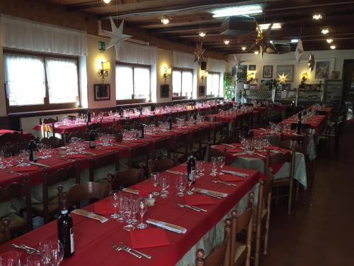a room with long tables with red table cloths and wine glasses at Albergo Chiara in Savignone