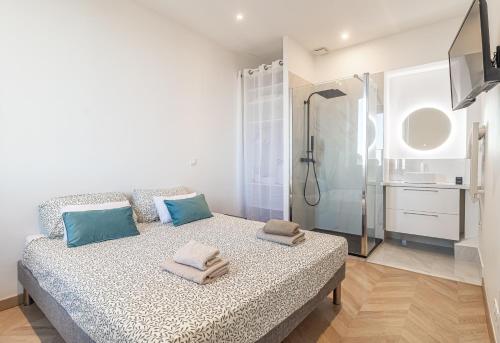 ein Schlafzimmer mit einem Bett mit blauen Kissen und einer Dusche in der Unterkunft T2 Town Center, Casino in Beausoleil