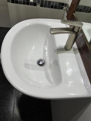 a white sink with a silver faucet in a bathroom at Tranquility Estate in Kingston