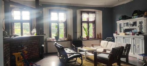 a living room with a couch and chairs and windows at Pensjonat Stara szkoła in Piaseczno