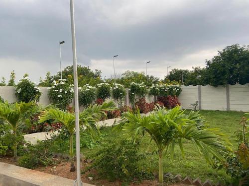 a garden with white flowers and plants in front of a fence at luxurious farmhouse VILLA GRAND in Venkatāpur