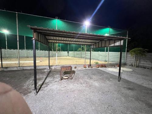 an empty tennis court at night with lights on at luxurious farmhouse VILLA GRAND in Venkatāpur