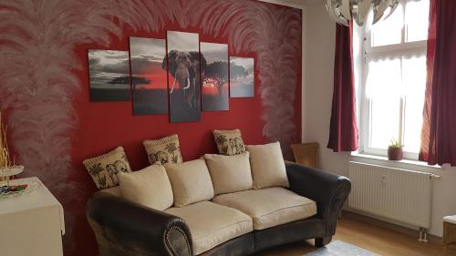 a living room with a couch against a red wall at FeWo Köt- 3 Ferienwohnungen im historischen Köthener Stadtkern in Köthen