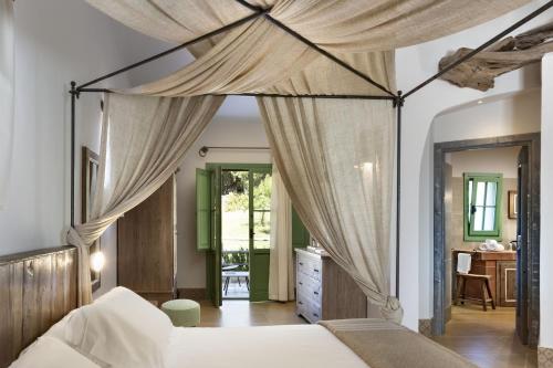 a bedroom with a canopy bed and a desk at Gallicantu Stazzo Retreat in Luogosanto