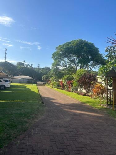 a brick road leading to a yard with trees and grass at Amanzimtoti , 36 Ocean Breeze ,warner beach, kingsburg in Kingsburgh