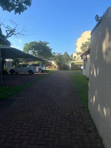 a brick road with a white car parked next to a building at Amanzimtoti , 36 Ocean Breeze ,warner beach, kingsburg in Kingsburgh