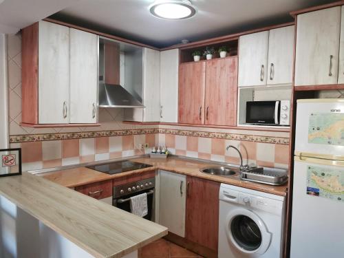 a kitchen with wooden cabinets and a sink and a dishwasher at Apartamento María Platero Céntrico y con las mejores vistas del casco antiguo la montaña y el mar mediterráneo in Frigiliana