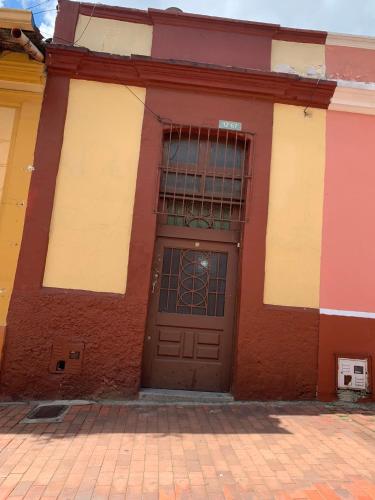 a red and white building with a brown door at Hermosa Casa en la Calendaria - centro histórico de la ciudad in Bogotá
