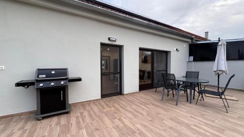 a patio with a table and chairs and a grill at Rózsa Vendégház in Kastélyosdombó
