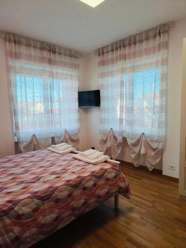 a bedroom with a bed and two large windows at Villa Petra - Πέτρα in Alpignano
