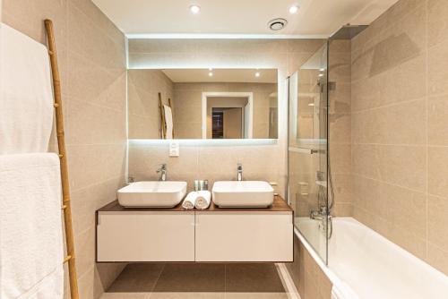 une salle de bain avec deux lavabos, une baignoire et un miroir dans l'établissement Appartement Nael - LES GETS, en plein centre et au pied des pistes, aux Gets