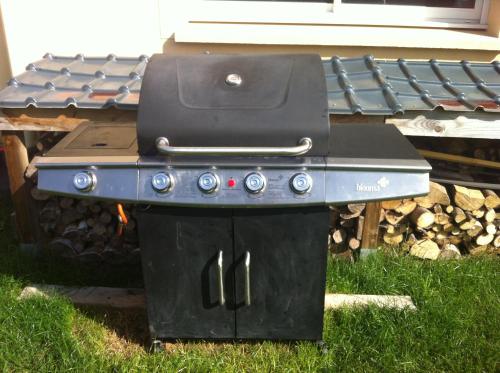 a grill sitting in the grass in front of a house at Maison Reine-Claude in Esbly
