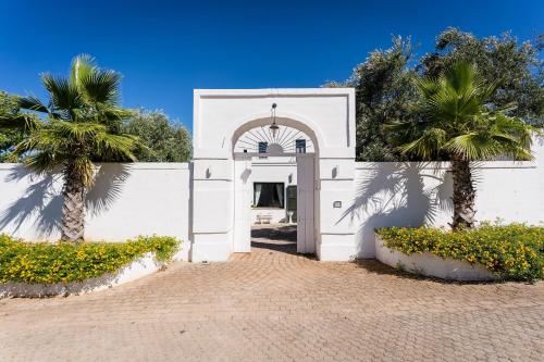 a white building with a gate and palm trees at Masseria Santa Teresa in Monopoli