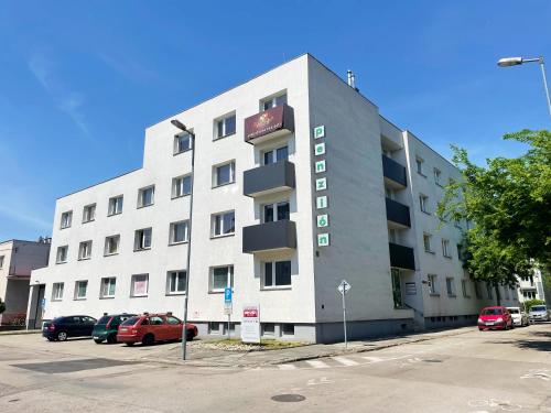 a large white building with cars parked in a parking lot at Penzión na Sihoti in Trenčín