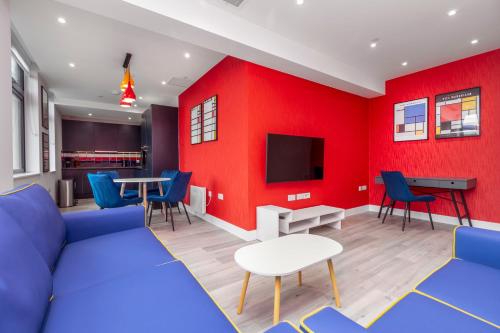 a living room with a blue couch and a red wall at Palm Tree House Apartments in Farnborough