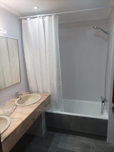 a bathroom with two sinks and a shower and a tub at Club Nautic in Cambrils