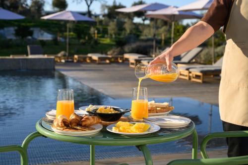 a person pouring orange juice onto a table of food at Quinta da Amendoeira - Évora - The Farmhouse in Évora