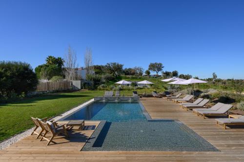 a swimming pool with lounge chairs and umbrellas at Quinta da Amendoeira - Évora - The Farmhouse in Évora