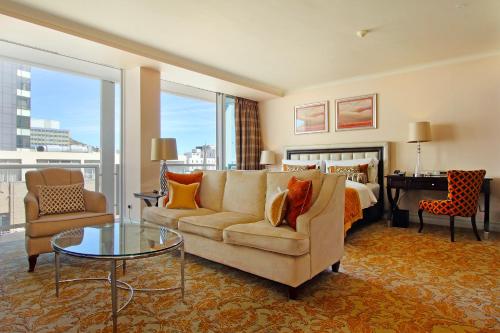 a hotel room with a bed and a couch and a table at Taj Cape Town - Spacious 5 star luxury residence with kitchenette in Cape Town