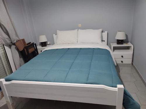 a bedroom with a bed with a blue blanket at Seven Seas Apartments in Artemida