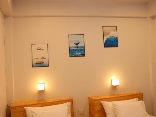a bedroom with two beds and three pictures on the wall at Moya Boutique Hotel in Betong