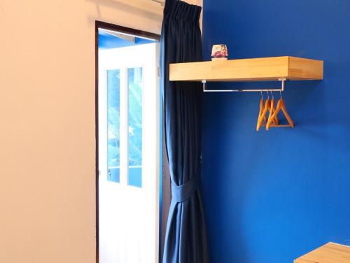 a room with a blue wall with a wooden shelf and a door at Moya Boutique Hotel in Betong