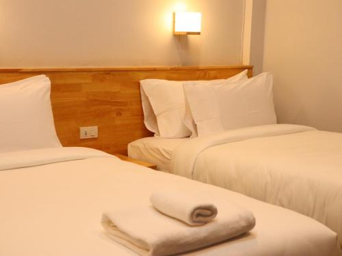 two beds in a hotel room with a towel on the bed at Moya Boutique Hotel in Betong