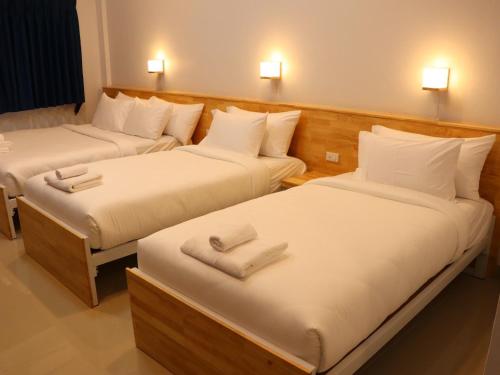 two beds in a hotel room with white sheets at Moya Boutique Hotel in Betong