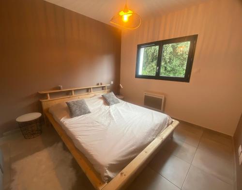 - une chambre avec un lit en bois avec des draps blancs et une fenêtre dans l'établissement Belle maison de garrigue, à Nîmes