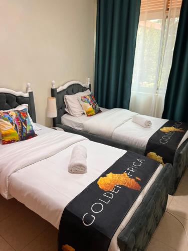 two beds sitting next to each other in a room at Kamona Living 3 Zimmer Apartment in Namugongo