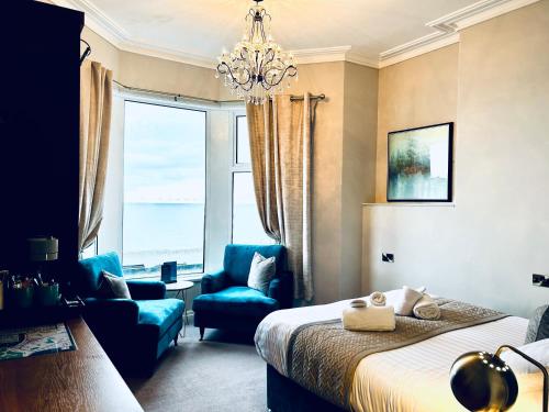 a bedroom with a bed and a chair and a window at Hotel No5, Beachfront with Free Private Car Park in Llandudno